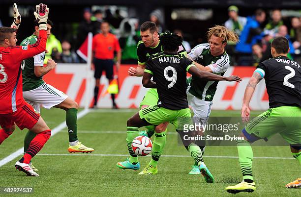 Obafemi Martins and Kenny Cooper of Seattle Sounders FC go after the ball with Michael Harrington of Portland Timbers during the second half of the...