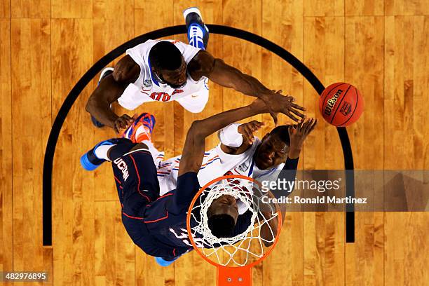 Amida Brimah of the Connecticut Huskies battles for a loose ball against Patric Young and Will Yeguete of the Florida Gators during the NCAA Men's...