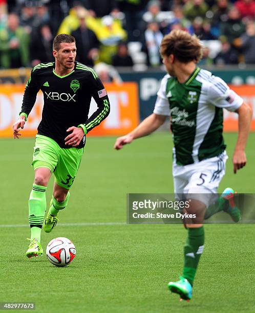 Kenny Cooper of Seattle Sounders FC brings the ball up the field on Michael Harrington of Portland Timbers during the first half of the game at...