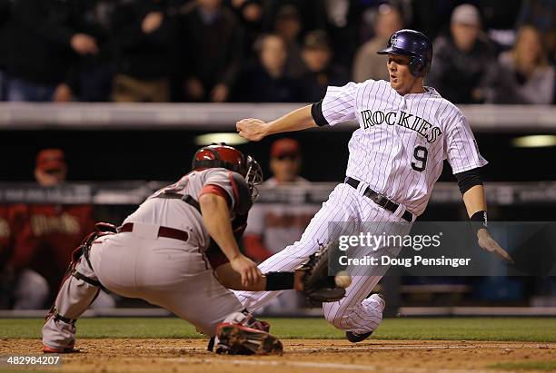 LeMahieu of the Colorado Rockies slides around catcher Miguel Montero of the Arizona Diamondbacks to score on a single by Carlos Gonzalez of the...