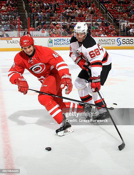 Jay Harrison of the Carolina Hurricanes takes the puck away from Jaromir Jagr of the New Jersey Devils during their NHL game at PNC Arena on April 5,...