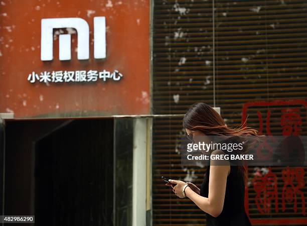 Woman walks past a Xiaomi logo outside a Xiaomi service center in Beijing on August 5, 2015. Chinese company Xiaomi was the largest smartphone vendor...