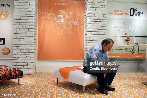 Customer sits and uses a smartphone inside a Euskaltel SA phone store in Barakaldo, Spain, on Tuesday, Aug. 4., 2015. Euskaltel, the phone and...
