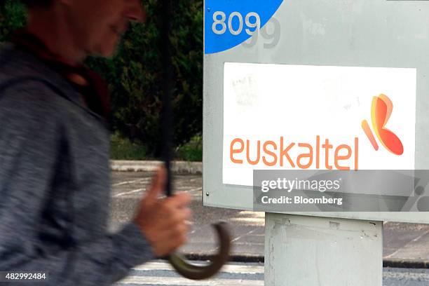 Pedestrian passes a Euskaltel logo outside the headquarters of Euskaltel SA in Barakaldo, Spain, on Tuesday, Aug. 4., 2015. Euskaltel, the phone and...