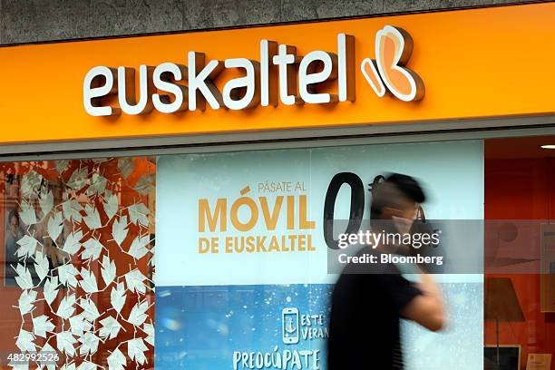 Pedestrian uses a smartphone as he walks past a Euskaltel SA phone store in Barakaldo, Spain, on Tuesday, Aug. 4., 2015. Euskaltel, the phone and...