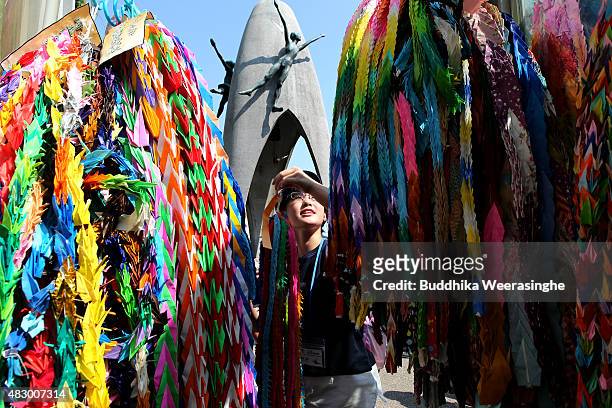 Boy offers colorful paper cranes at the Children's Peace Monument to honor the victims of the 1945 Atomic bomb, at the Hiroshima Peace Memorial Park...
