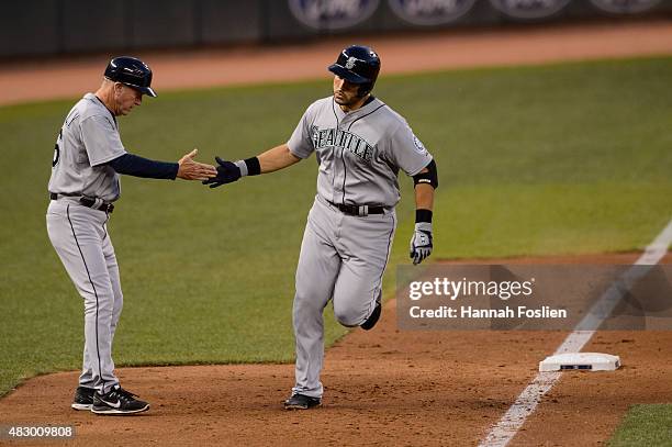 Third base coach Rich Donnelly of the Seattle Mariners congratulates Jesus Montero on hitting a home run against the Minnesota Twins during the game...