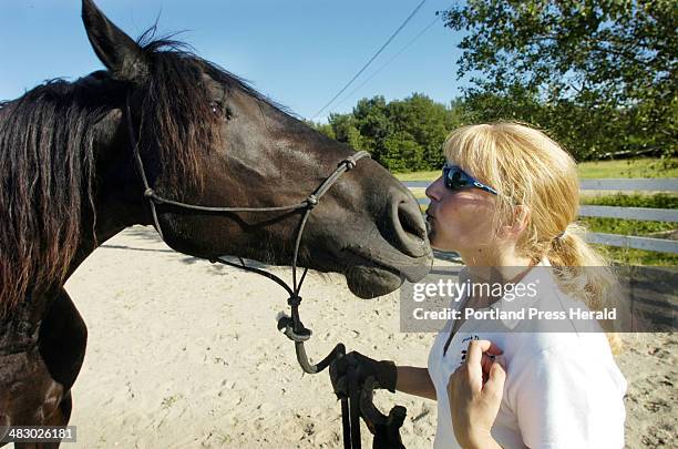 Wednesday, July 19, 2006: Cindi Spear gets a kiss from her horse "MaLynn," a two-year-old Friesian, at the Hollis Equestrian Park. The park has a...