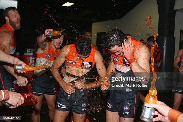 Joshua Kelly of the Giants and Lachie Plowman of the Giants are showered with drinks as they celebrate victory during the round three AFL match...