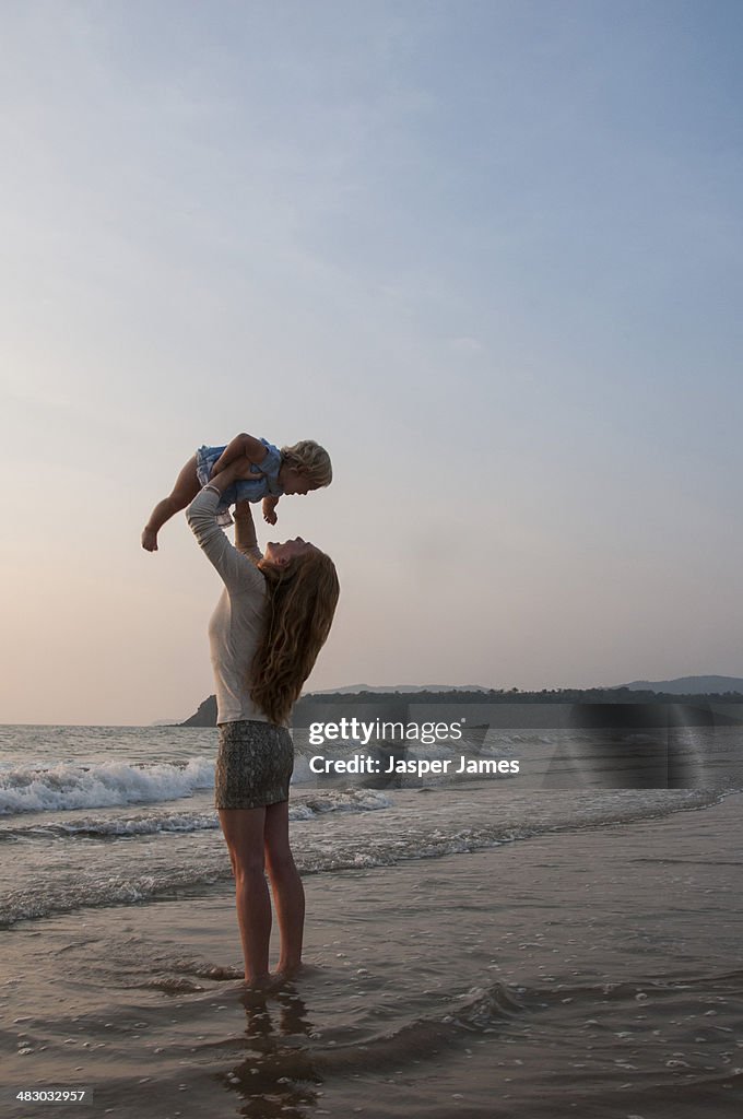 Woman holding her baby in the air at the beach,Goa