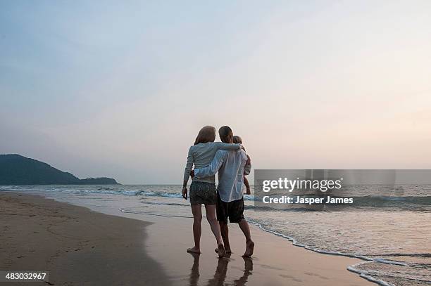 family walking on the beach at sunset - girl beach sunset stock-fotos und bilder