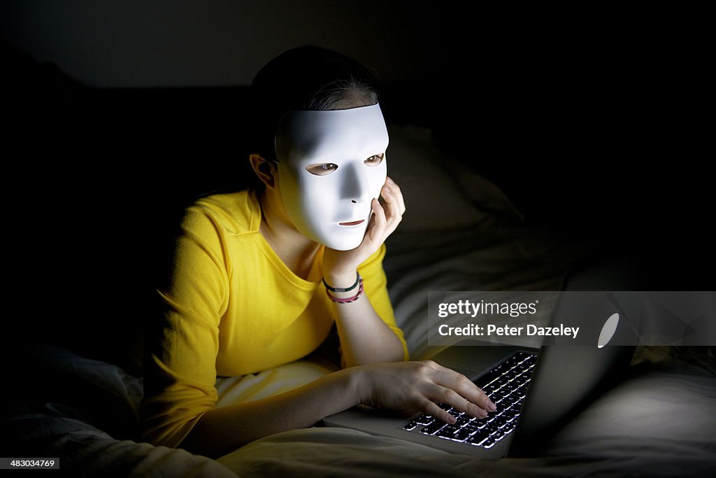 Anonymous teenager in mask on internet at night