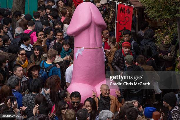 People pose for photos in front of a large pink phallic-shaped 'Mikoshi' during Kanamara Matsuri on April 6, 2014 in Kawasaki, Japan. The Kanamara...