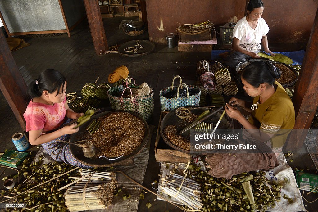 Women make cheroots, the traditional Myanmar cigar, in a...