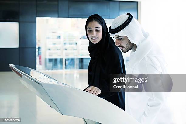 arab family using interactive screen of digital kiosk - elektromarkt stockfoto's en -beelden