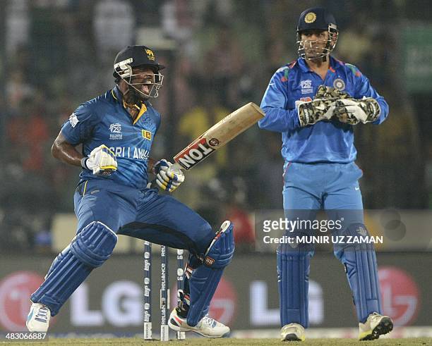 Sri Lankan cricketer Thisara Perera reacts following his team's win as India cricket captain Mahendra Singh Dhoni looks on during the ICC World...