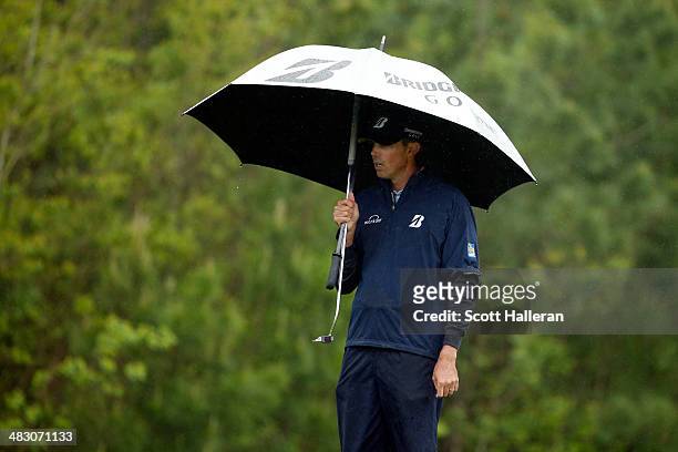 Matt Kuchar of the United States holds an umbrella as rain falls on the green of the eighth hole during the final round of the Shell Houston Open at...