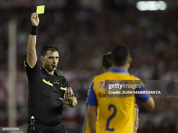 Uruguayan referee Dario Agustin Ubriaco shows a yellow card to Israel Jimenez of Mexico's Tigres during their Libertadores Cup second leg final match...