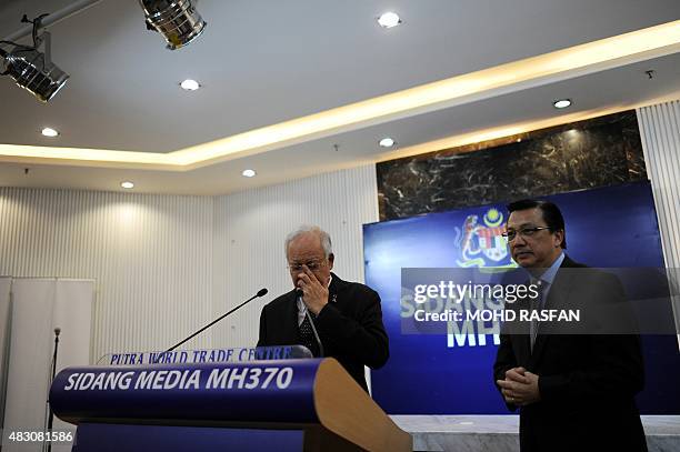 This picture taken early on August 6, 2015 shows Malaysias Prime Minister Najib Razak adjusting his glasses as Malaysia's Transport Minister Liow...