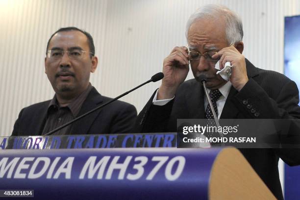 This picture taken early on August 6, 2015 shows Malaysia's Prime Minister Najib Razak adjusting his glasses before delivering a statement during a...