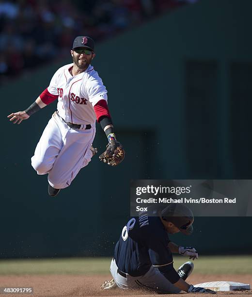 Dustin Pedroia of the Boston Red Sox jumps in an attempt to catch an errant throw as Ryan Braun of the Milwaukee Brewers slides into second with a...