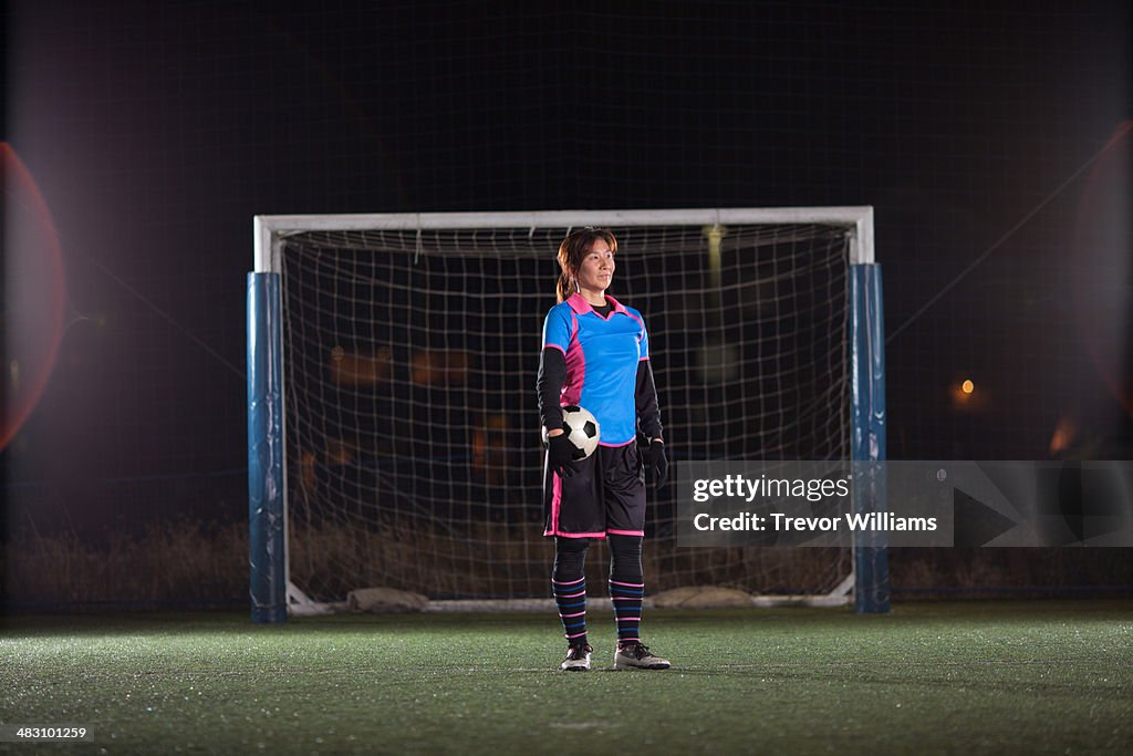 Female goalkeeper with ball in front of the goal