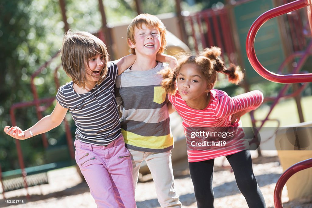 Three playful multiracial children on playground