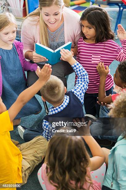 teacher in class with multiracial group of preschoolers - kids reading in classroom stock pictures, royalty-free photos & images