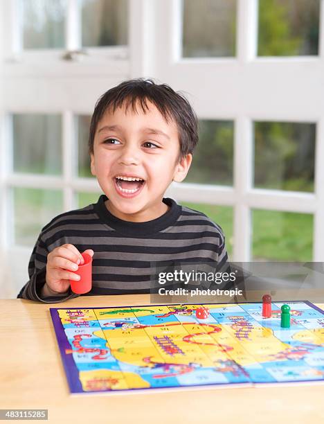 happy boy playing board game - snakes and ladders stock pictures, royalty-free photos & images