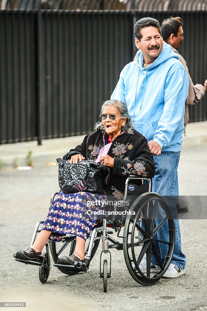 Man pushing wheelchair with disabled senior woman