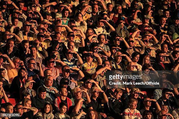 Watford fans shield their eyes from the low evening sun during the pre season match beween Watford and Sevilla at Vicarage Road on July 31, 2015 in...