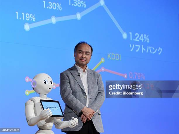 Billionaire Masayoshi Son, chairman and chief executive officer of SoftBank Group Corp., right, looks on as the company's humanoid robot Pepper...