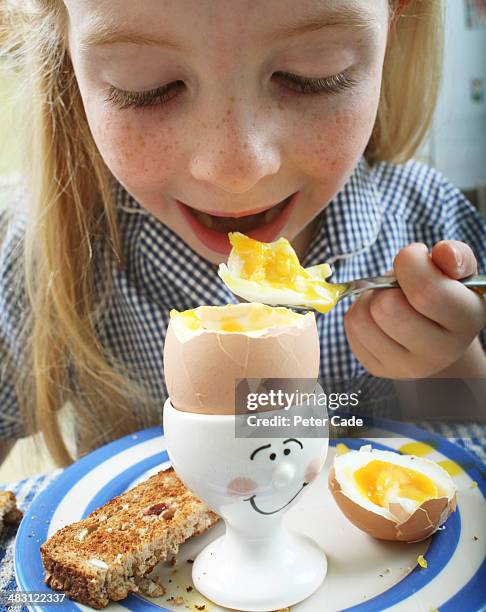 young school girl eating egg for breakfast - breakfast eggs stockfoto's en -beelden
