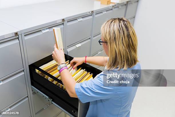 infirmière est vérifier carte d'index de patients dans le classeur à tiroirs - filing cabinet photos et images de collection