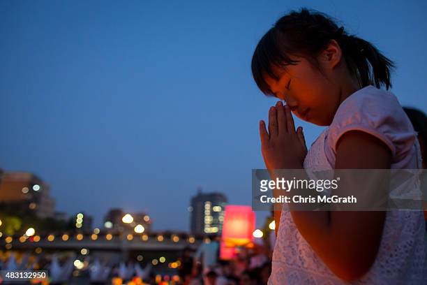 Young girl prays after floating a candle lit paper lantern on the river during 70th anniversary activities, comemorating the atomic bombing of...