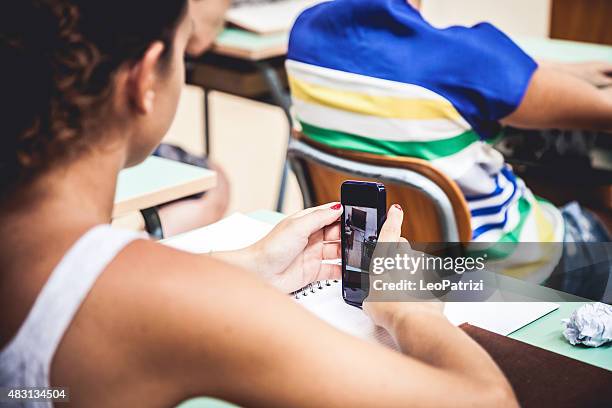 young student playing on smarphone during lesson - cyberbullying stockfoto's en -beelden