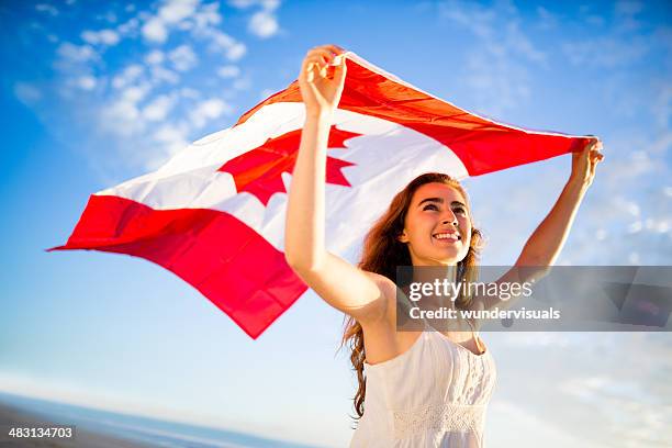 woman holding canadian flag against sky - canada patriotism stock pictures, royalty-free photos & images