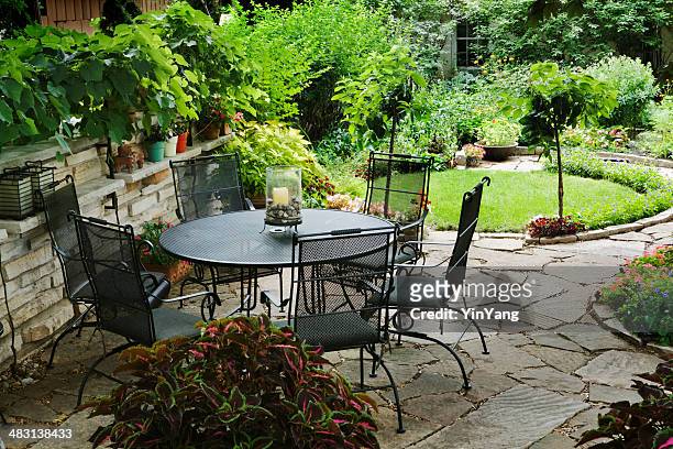 patio furniture in yard with flower beds, landscaped ornamental garden - stone patio stock pictures, royalty-free photos & images
