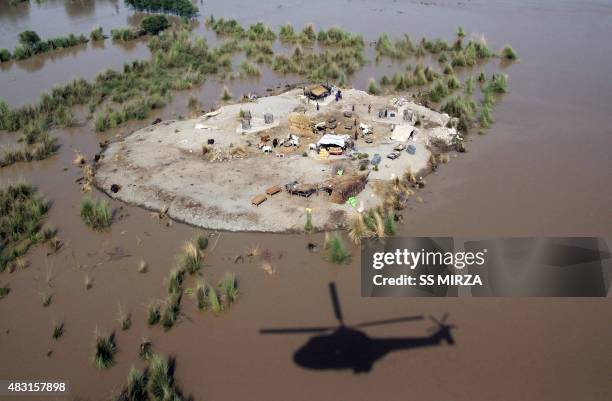 The shadow of a Pakistani army helicopter is seen next to land surrounded by flood water where affected villagers gathered to seek higher ground in...