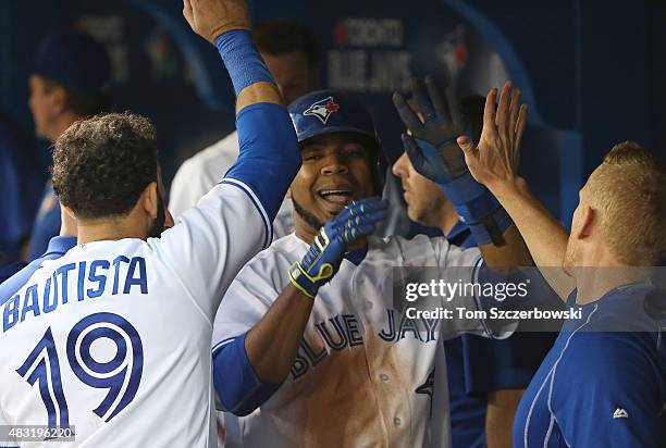 Edwin Encarnacion of the Toronto Blue Jays is congratulated by Jose Bautista and strength & conditioning coach Chris Joyner after scoring a run in...