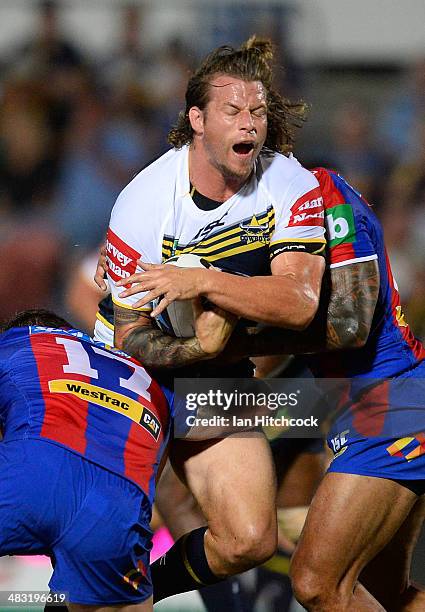 Ashton Sims of the Cowboys is tackled by Adam Cuthbertson and c of the Knights during the round five NRL match between the North Queensland Cowboys...