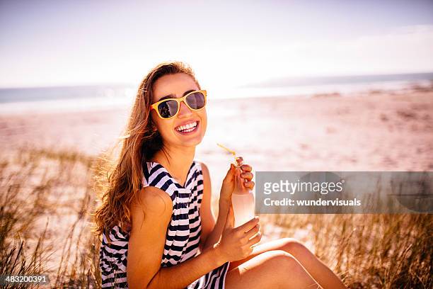 lächelnde frau trinkt limonade am strand - lemon soda stock-fotos und bilder
