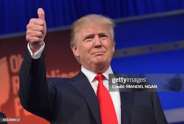 Real estate tycoon Donald Trump flashes the thumbs-up as he arrives on stage for the start of the prime time Republican presidential debate on August...