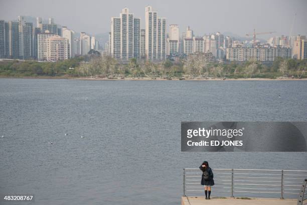 Woman stands before the Han river in Seoul on April 7, 2014. Spring time in South Korea typically lasts from April to June, and features mild...