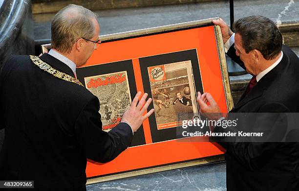 Stefan Schostock , mayor of the town of Hanover, hands over a present to former German Chancellor Gerhard Schroeder at a reception to celebrate his...