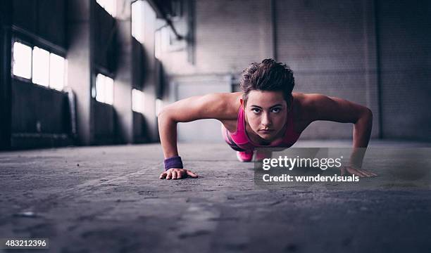 woman doing push ups with determination in  industrial space - daily sport girls bildbanksfoton och bilder