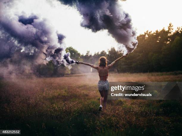 hippie girl running through field with purple smoke flares - public park design stock pictures, royalty-free photos & images