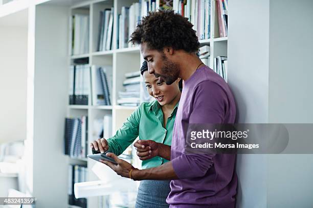 work companions reviewing ideas on digital tablet - viola colore foto e immagini stock