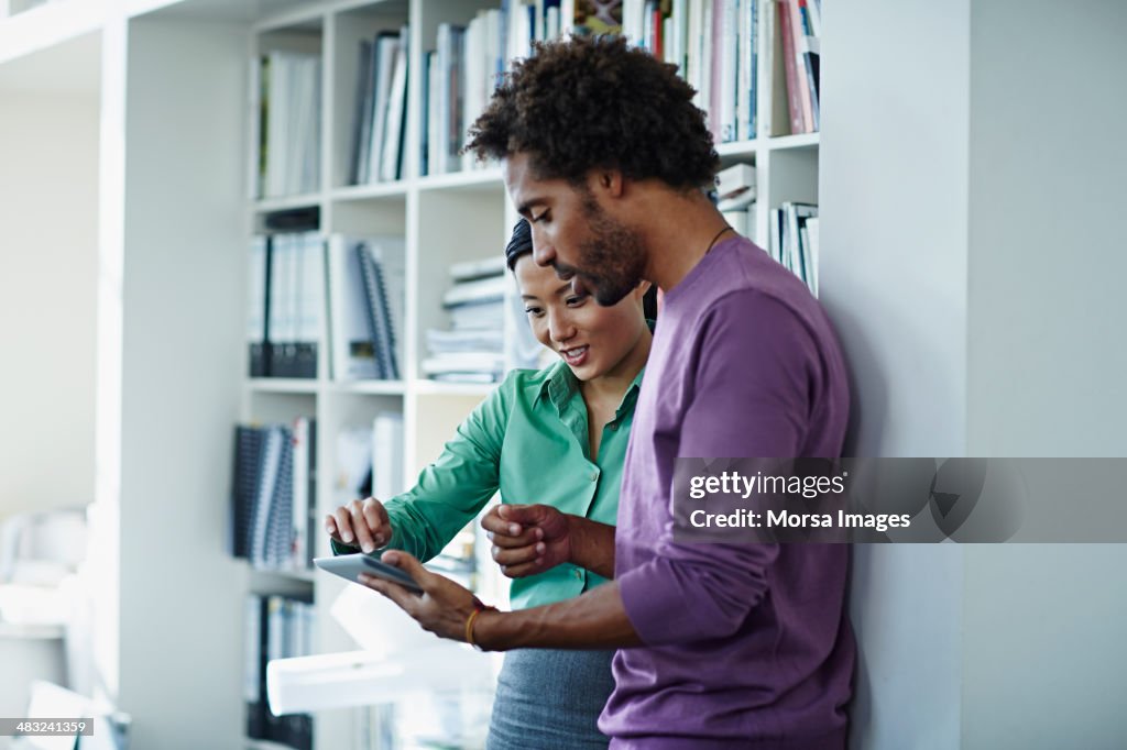 Work companions reviewing ideas on digital tablet