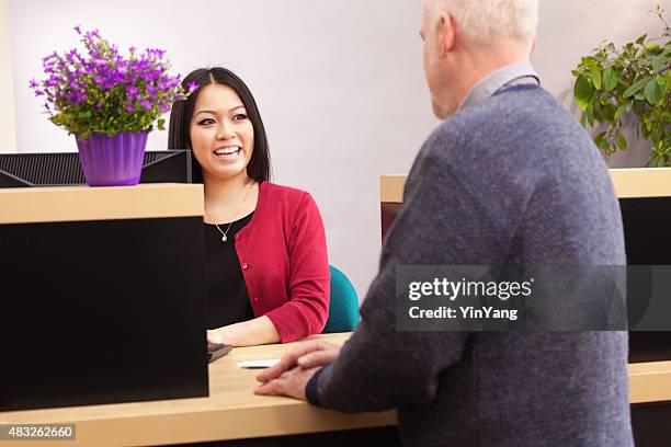 bank teller serving customer over retail banking service counter - bankpersoneel stockfoto's en -beelden